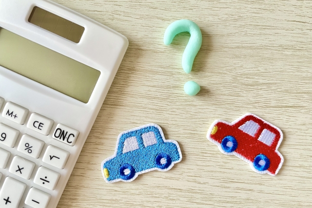 電卓の横に並べられた2台の車とクエスチョンマークのモチーフ