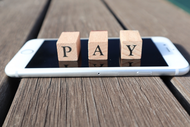 スマホの上に並んでいるPAYと印字された木製のブロック