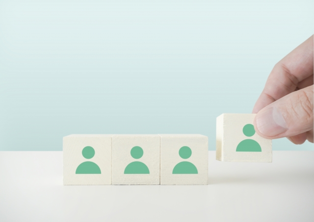 人型のピクトグラムが印字されたブロックを並べている人の手元