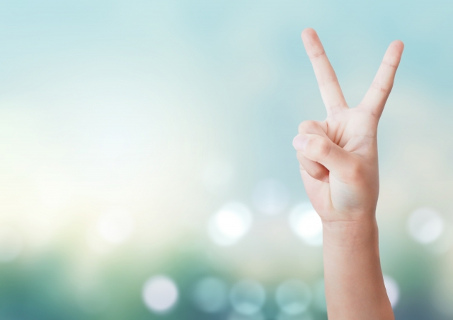 右手でピースサインをしている人の手