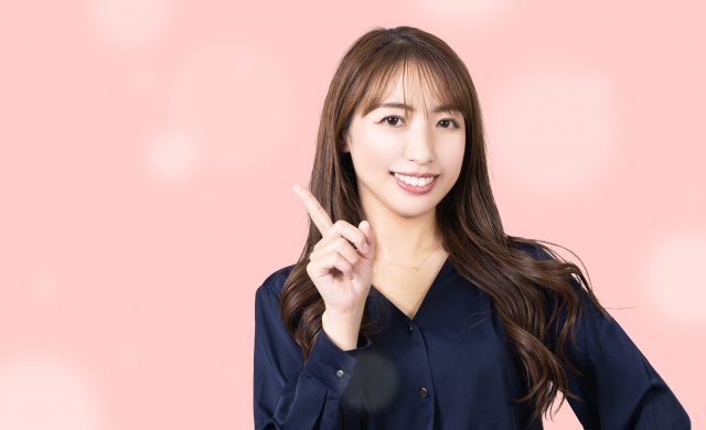 人さし指を立ててこちらを向いている笑顔の女性