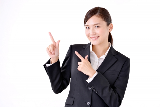 右上を両手で指さしている笑顔の女性