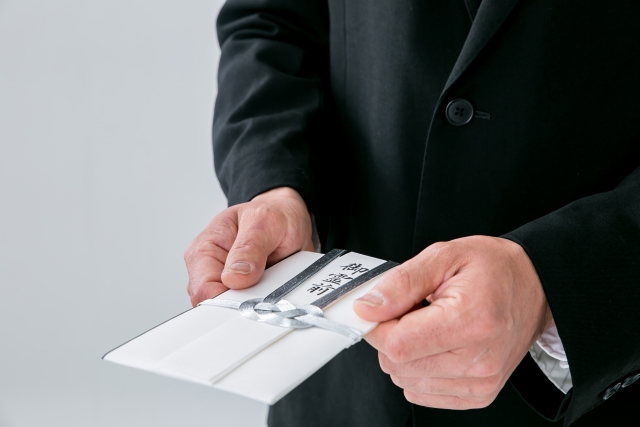 香典を渡そうとしている喪服姿の男性