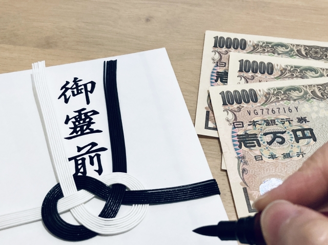 香典を書いている手元と3枚の1万円札