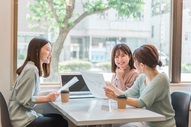 書類を手に座って談笑している3人の女性