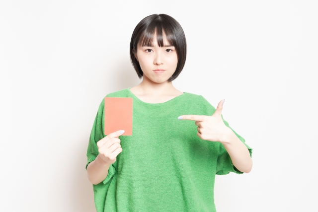 右手に持ったレッドカードを指さす女性