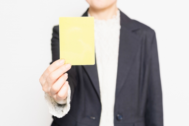 イエローカードを持つ女性の手元