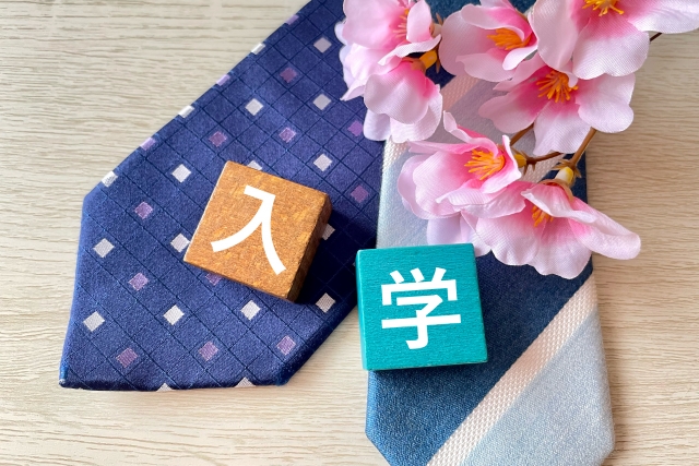 2本のネクタイの上に置かれた入学と印字されたブロック