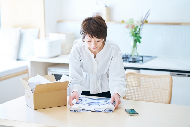 畳んだ衣類を箱に収めようとしている女性