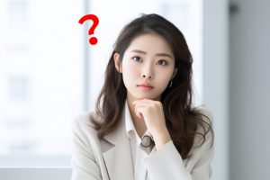 顎の下に手を添えながら何かを考えている女性