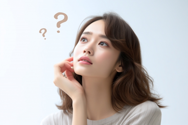 考えている様子の女性とクエスチョンマーク