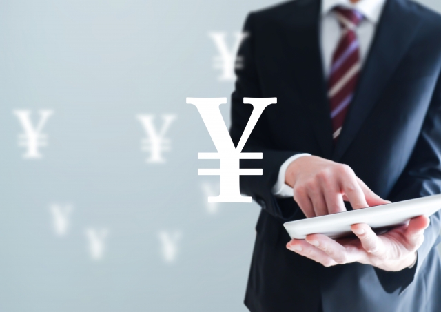 タブレットを操作しているスーツ姿の男性と円マーク