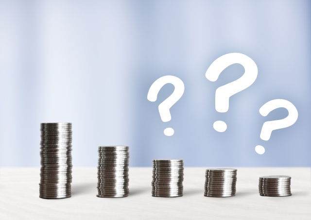 積み上げられた硬貨と3つのクエスチョンマーク