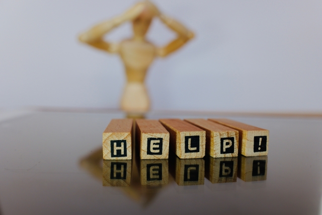 頭を抱えているデッサン人形の前に置かれているHELP!と印字されたブロック