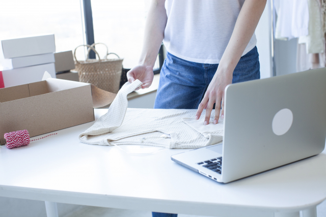 テーブルの上でニットを畳んでいる女性の手元