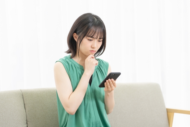 スマホを眺めながら考える女性