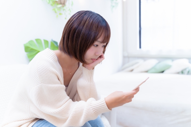 スマホを見て悩む女性