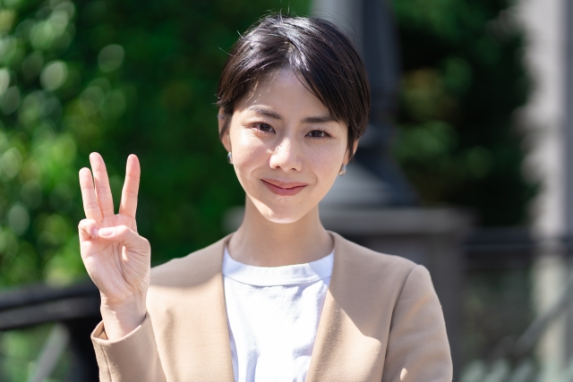指で数字の三を表す女性