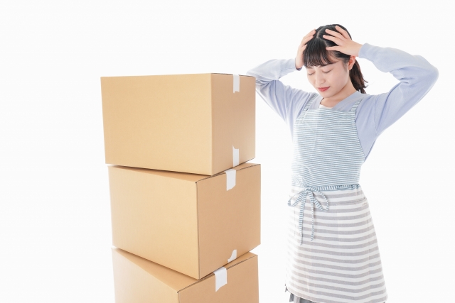 ダンボールの横で頭をかかえる女性