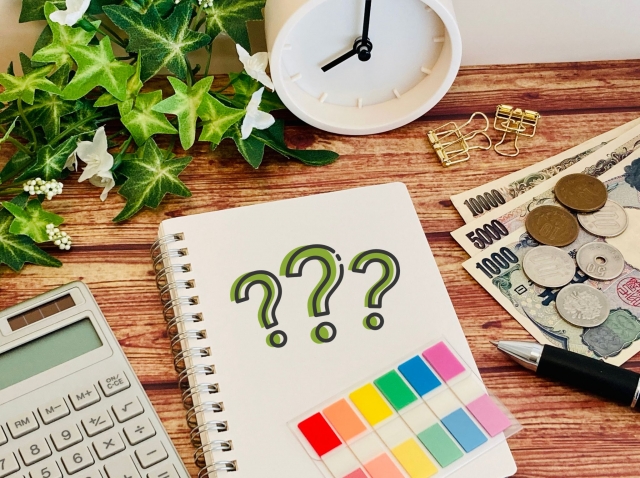 ハテナマークが書かれたノートとお金