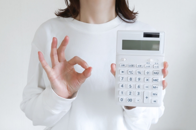 計算機を持ってOKサインをする女性