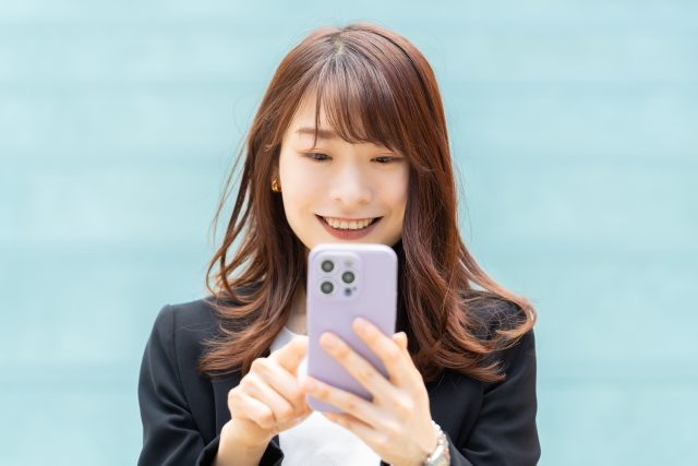スマホを操作する笑顔のビジネスウーマン