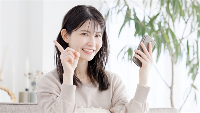 スマホを操作しながら指差しをする笑顔の女性