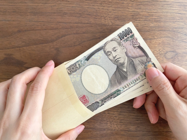 机上で10万円が入った茶封筒を持つ手元